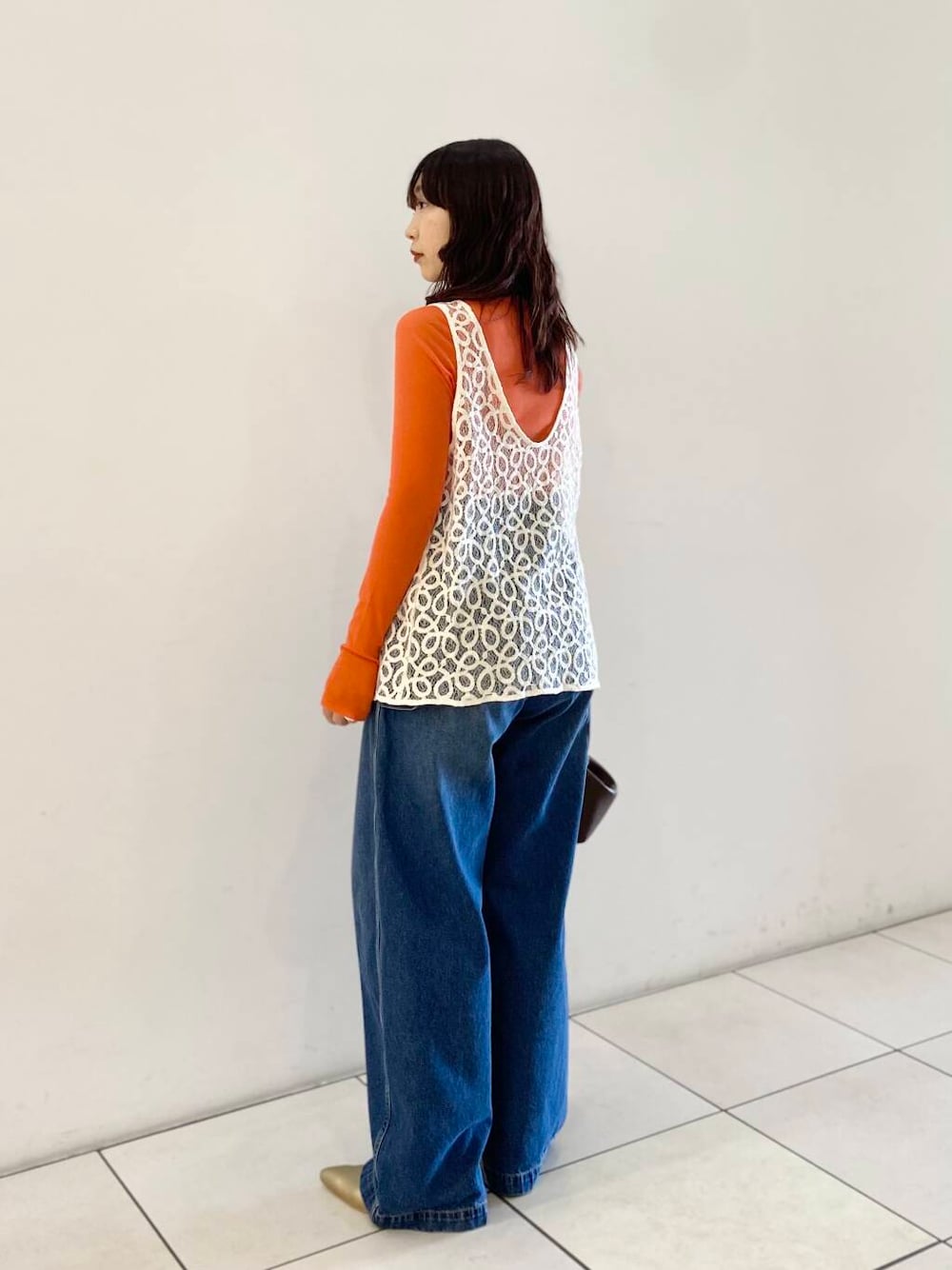 ゴールド系のパンプス、ブルー系のデニムパンツ、オレンジ系のTシャツ/カットソーを着用したレディースの夏コーディネートの3枚目の写真