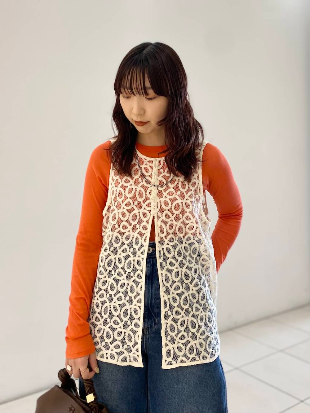 ゴールド系のパンプス、ブルー系のデニムパンツ、オレンジ系のTシャツ/カットソーを着用したレディースの夏コーディネートの4枚目の写真