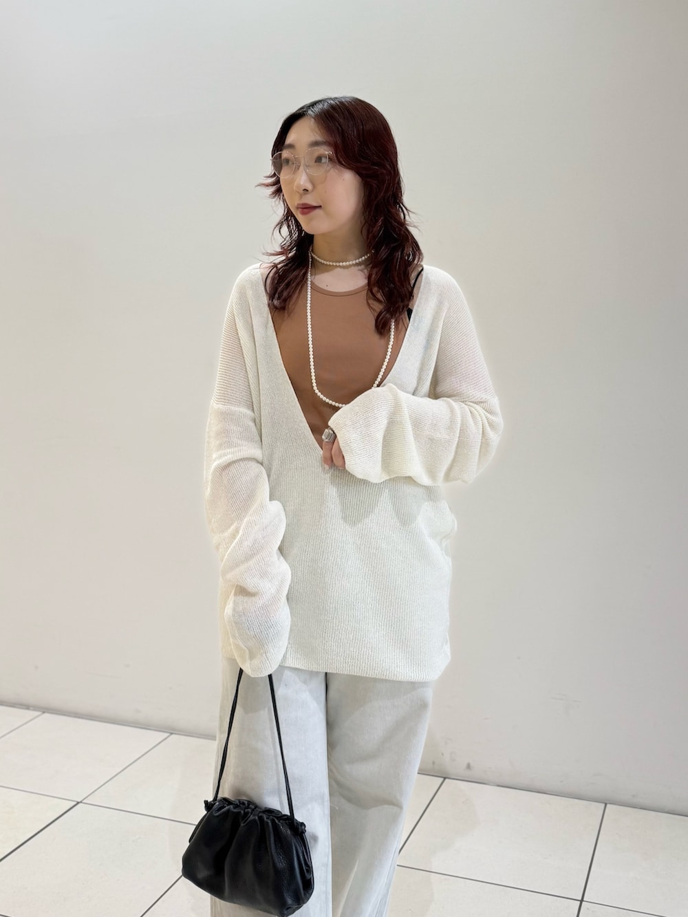 ブラック系のパンプス、オレンジ系のタンクトップ、ホワイト系のニット/セーターを着用したレディースの春コーディネートの5枚目の写真