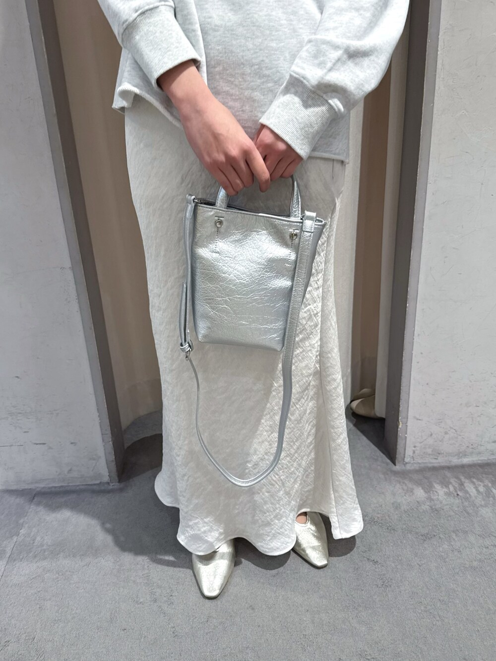 グレー系のスウェット、シルバー系のトートバッグ、ホワイト系のスカートを着用したレディースの春コーディネートの4枚目の写真
