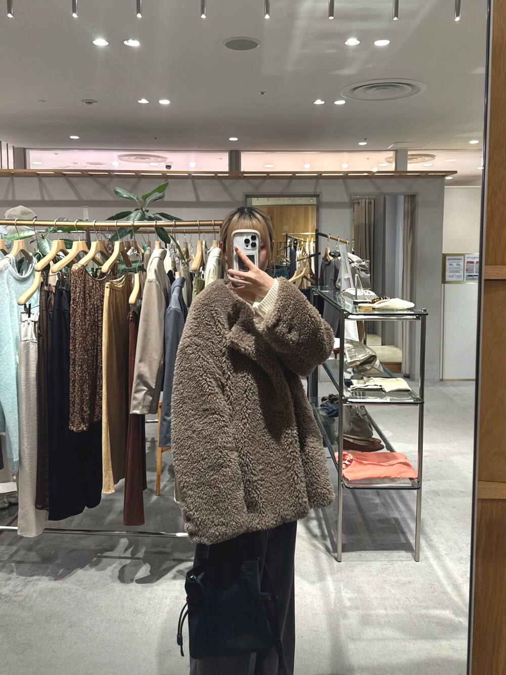 ブラウン系のその他アウター、ホワイト系のニット/セーター、ブラック系のトートバッグを着用したレディースの秋コーディネートの2枚目の写真