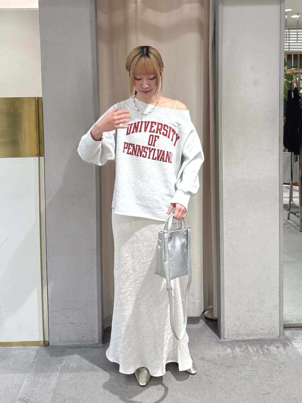 グレー系のスウェット、シルバー系のトートバッグ、ホワイト系のスカートを着用したレディースの春コーディネートの2枚目の写真