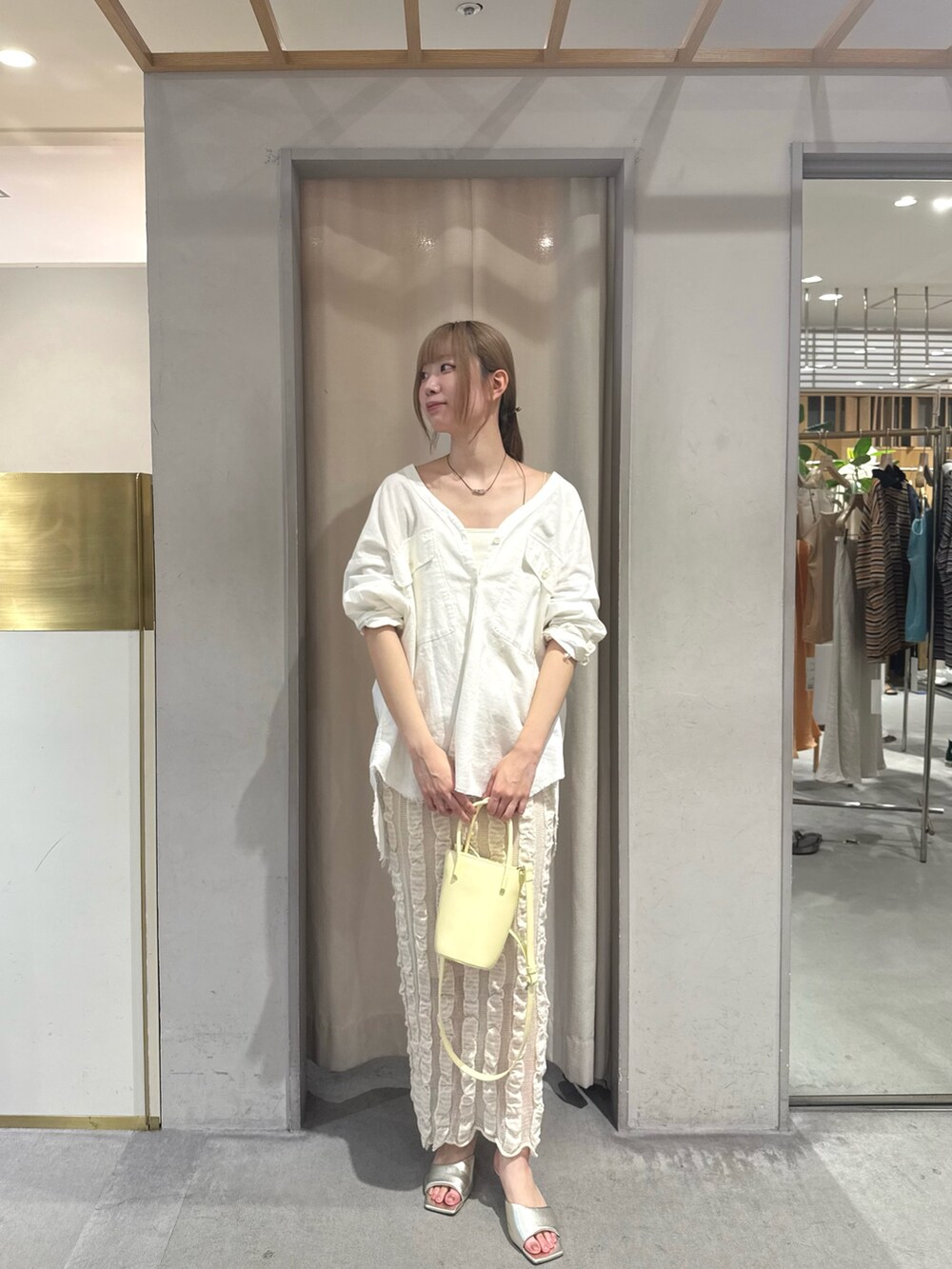 ホワイト系のシャツ/ブラウス、イエロー系のトートバッグ、ベージュ系のスカートを着用したレディースの夏コーディネートの2枚目の写真