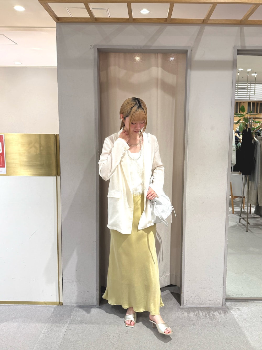 イエロー系のスカート、ゴールド系のサンダル、シルバー系のトートバッグを着用したレディースの夏コーディネートの2枚目の写真