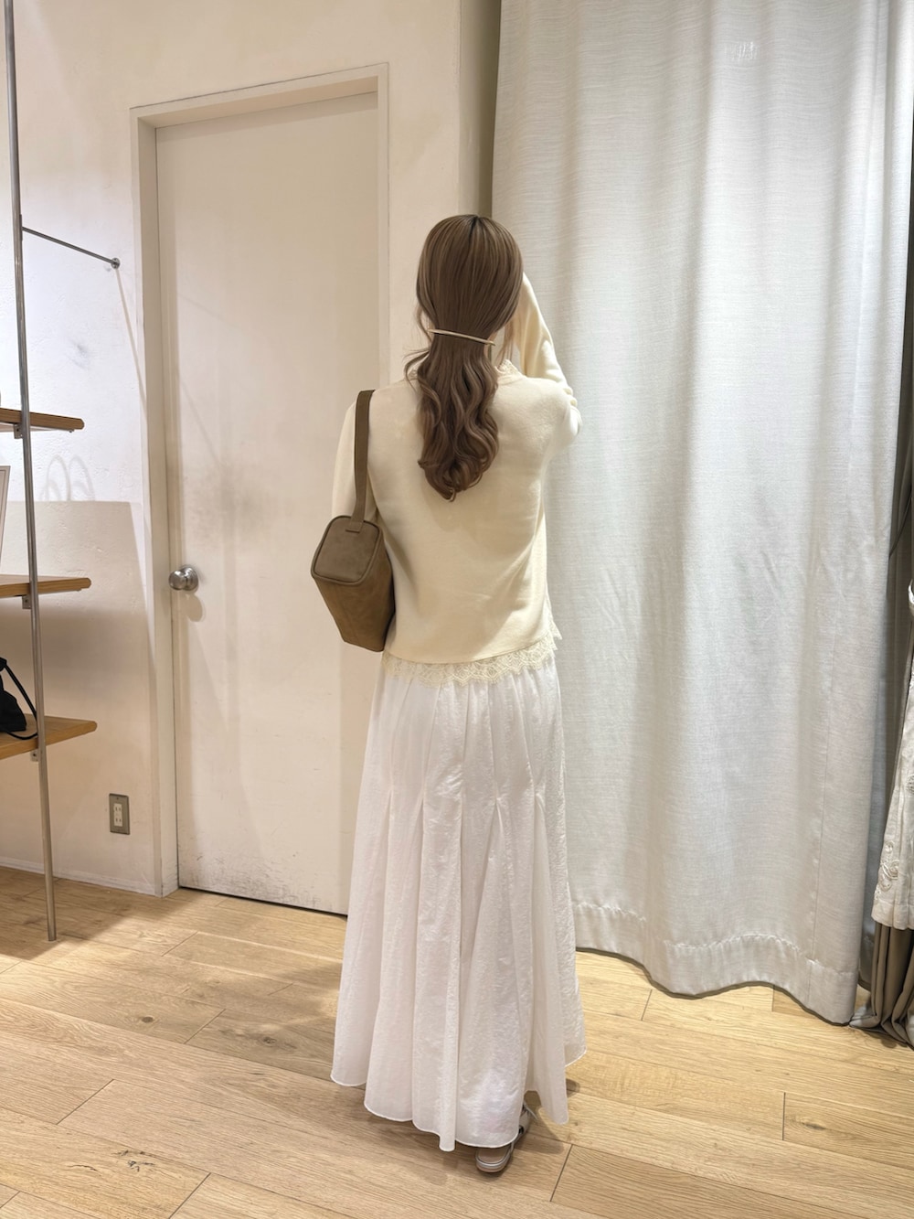 ホワイト系のカーディガン/ボレロ、ベージュ系のトートバッグ、ホワイト系のスカートを着用したレディースの秋コーディネートの3枚目の写真