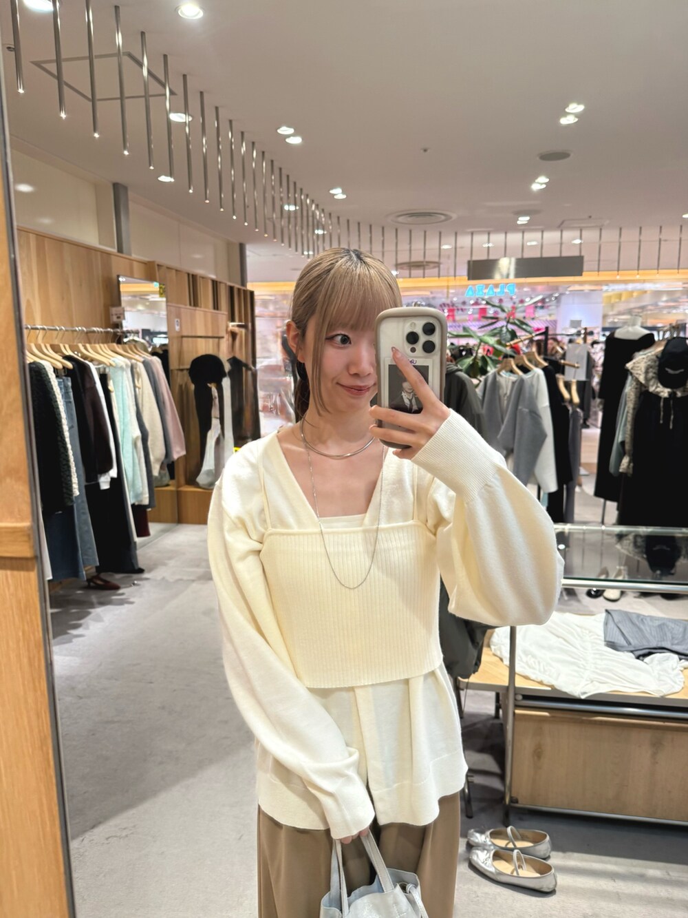 シルバー系のトートバッグ、ベージュ系のスラックス、ゴールド系のパンプスを着用したレディースの秋コーディネートの2枚目の写真