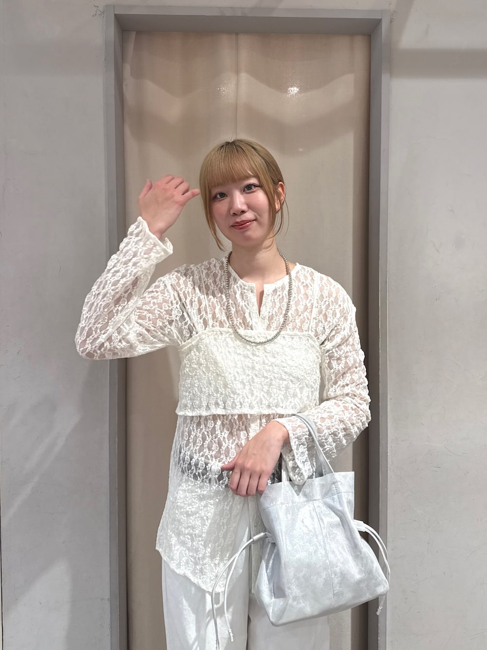 シルバー系のトートバッグ、ホワイト系のデニムパンツ、グレー系のサンダルを着用したレディースの春コーディネートの2枚目の写真