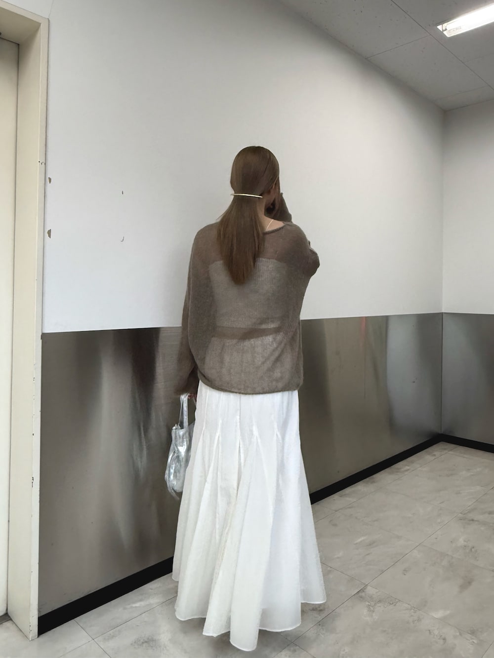 ベージュ系のニット/セーター、シルバー系のトートバッグ、ホワイト系のスカートを着用したレディースの秋コーディネートの3枚目の写真