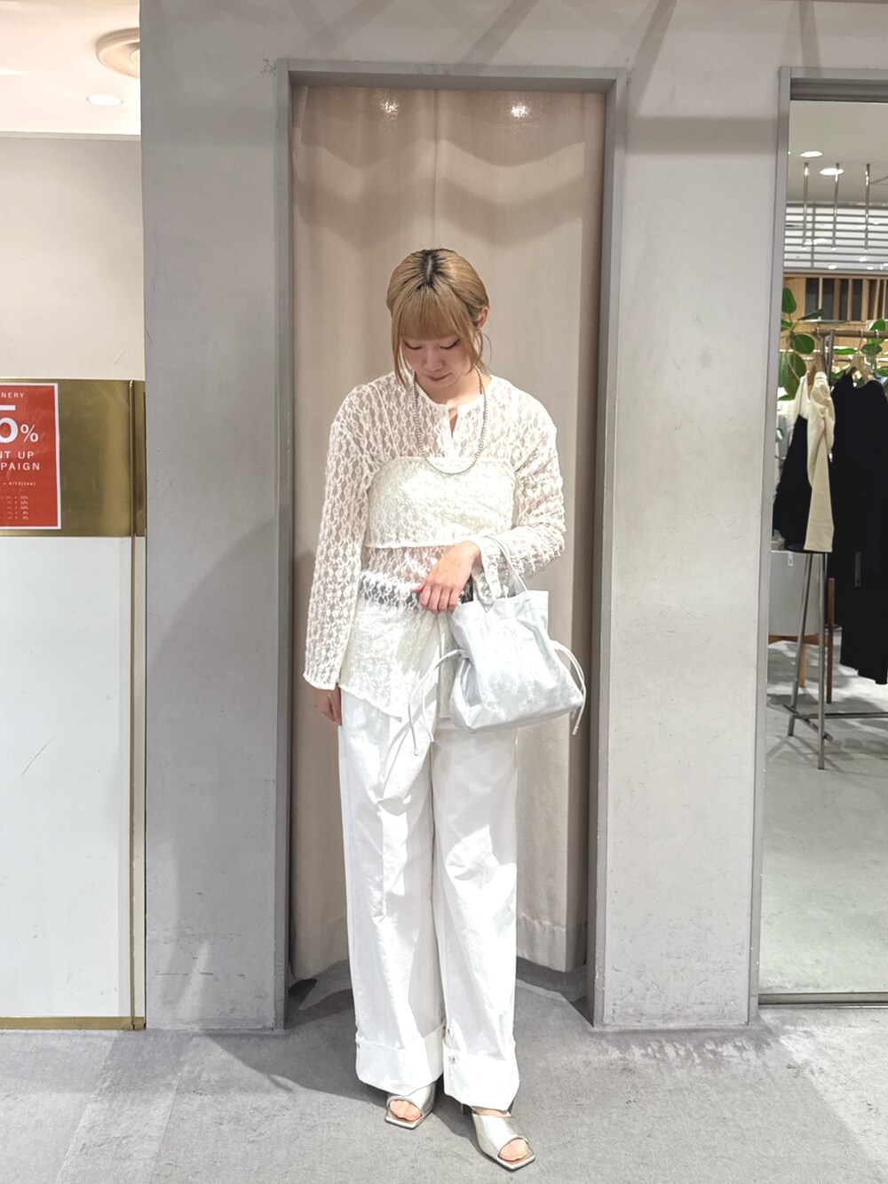 シルバー系のトートバッグ、ホワイト系のデニムパンツ、グレー系のサンダルを着用したレディースの春コーディネートの3枚目の写真