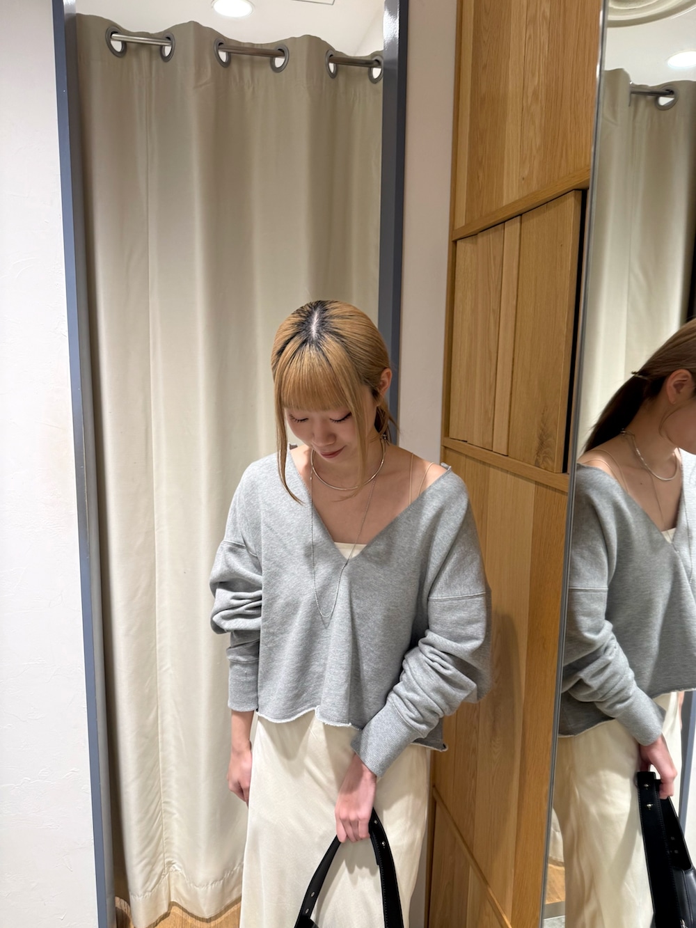 グレー系のスウェット、ブラック系のトートバッグ、ホワイト系のスカートを着用したレディースの春コーディネートの2枚目の写真