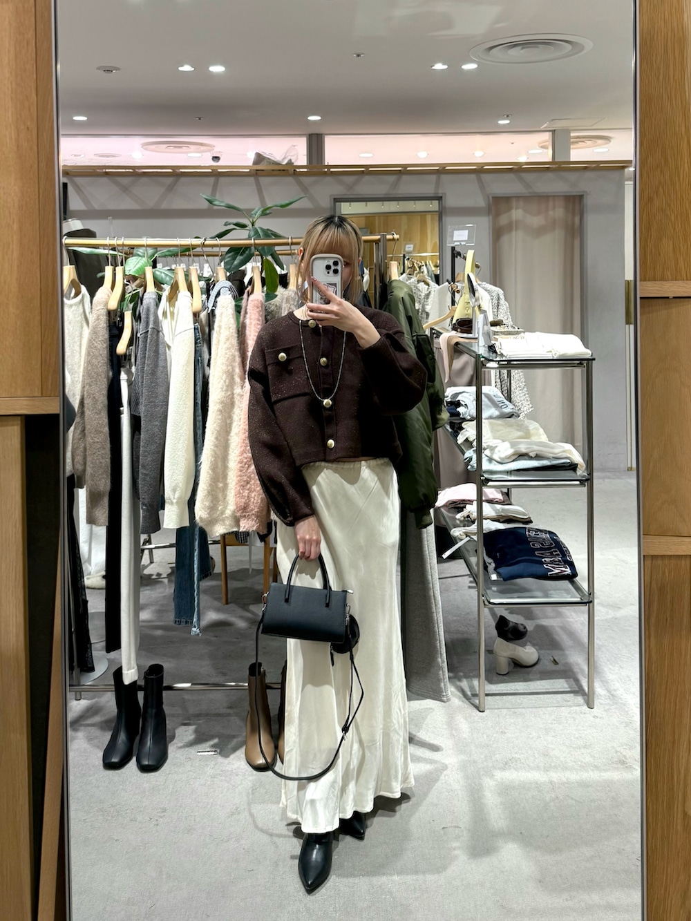 ブラウン系のカーディガン/ボレロ、ホワイト系のスカート、ブラック系のトートバッグを着用したレディースの冬コーディネートの2枚目の写真