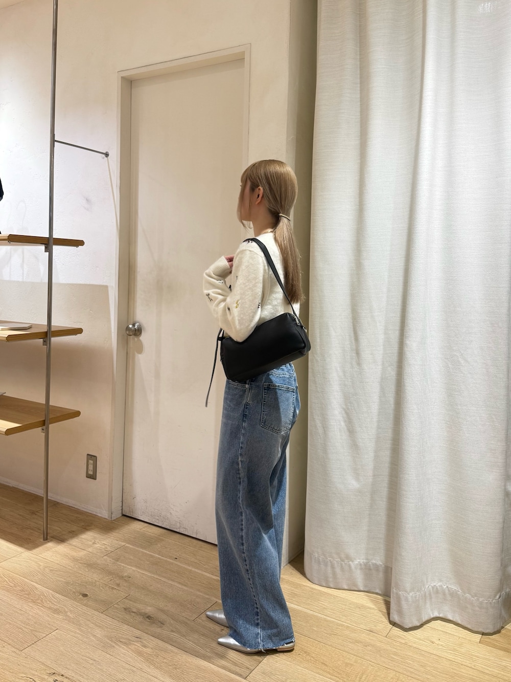 ホワイト系のカーディガン/ボレロ、ブラック系のショルダーバッグ、ブルー系のデニムパンツを着用したレディースの秋コーディネートの3枚目の写真