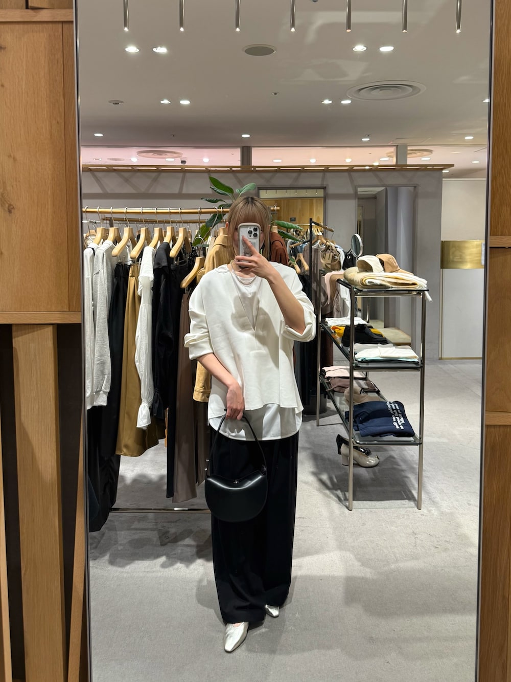 ブラック系のスラックス、ブラック系のトートバッグ、ゴールド系のパンプスを着用したレディースの秋コーディネートの2枚目の写真