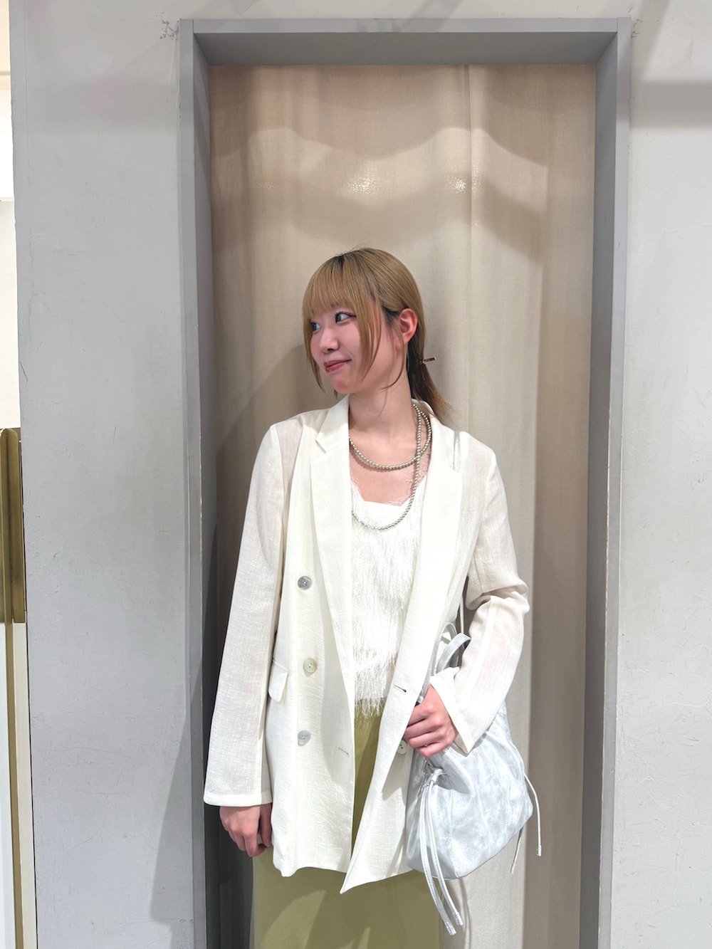 イエロー系のスカート、ゴールド系のサンダル、シルバー系のトートバッグを着用したレディースの夏コーディネートの3枚目の写真