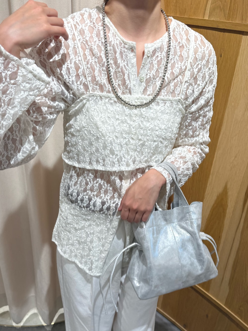 シルバー系のトートバッグ、ホワイト系のデニムパンツ、グレー系のサンダルを着用したレディースの春コーディネートの5枚目の写真