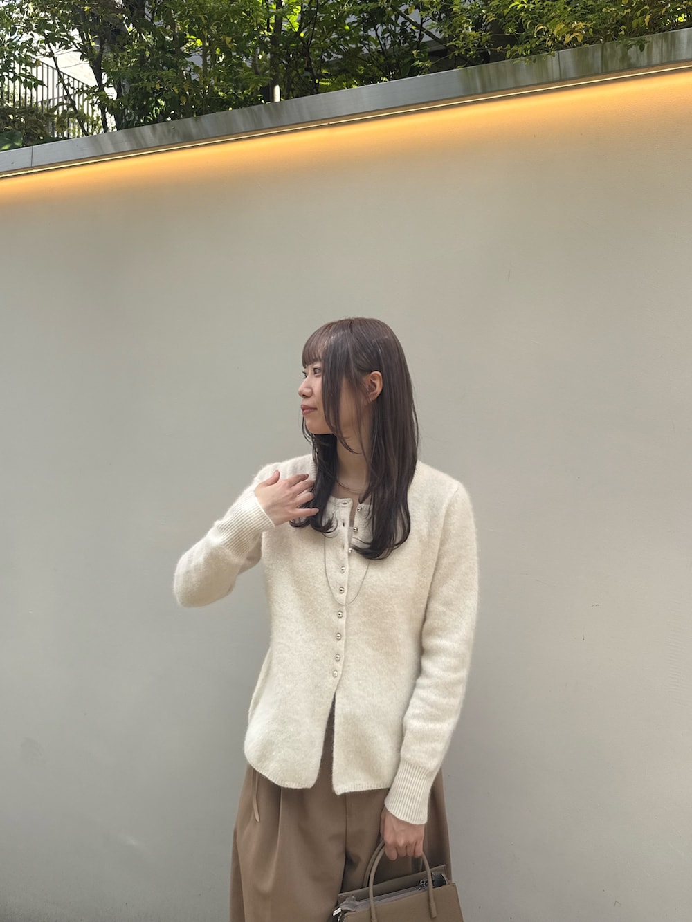 ホワイト系のカーディガン/ボレロ、ベージュ系のスラックス、ベージュ系のトートバッグを着用したレディースの秋コーディネートの2枚目の写真