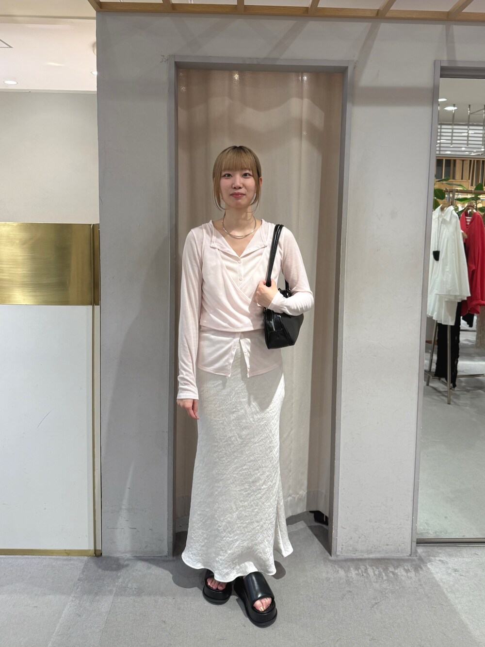 ホワイト系のスカート、ブラック系のサンダル、ブラック系のトートバッグを着用したレディースの夏コーディネートの2枚目の写真