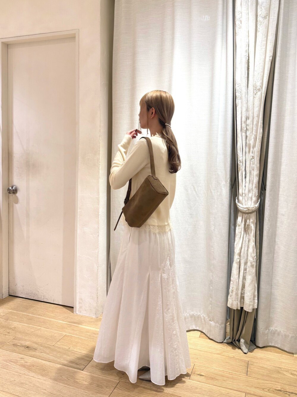 ホワイト系のカーディガン/ボレロ、ベージュ系のトートバッグ、ホワイト系のスカートを着用したレディースの秋コーディネートの2枚目の写真