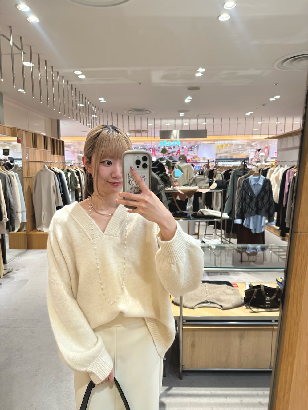 ホワイト系のニット/セーター、ブラック系のトートバッグ、ベージュ系のスカートを着用したレディースの冬コーディネートの2枚目の写真