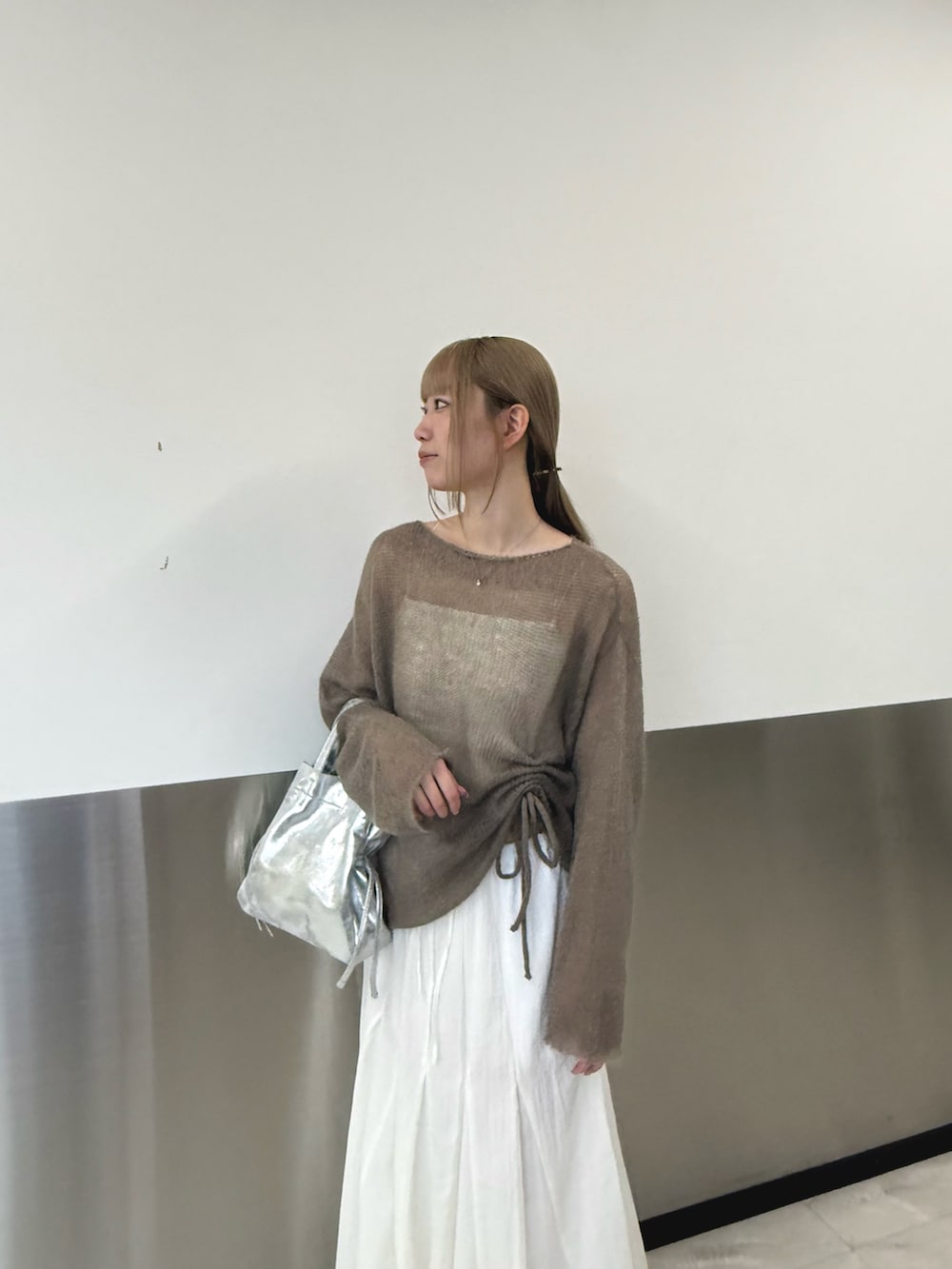 ベージュ系のニット/セーター、シルバー系のトートバッグ、ホワイト系のスカートを着用したレディースの秋コーディネートの4枚目の写真