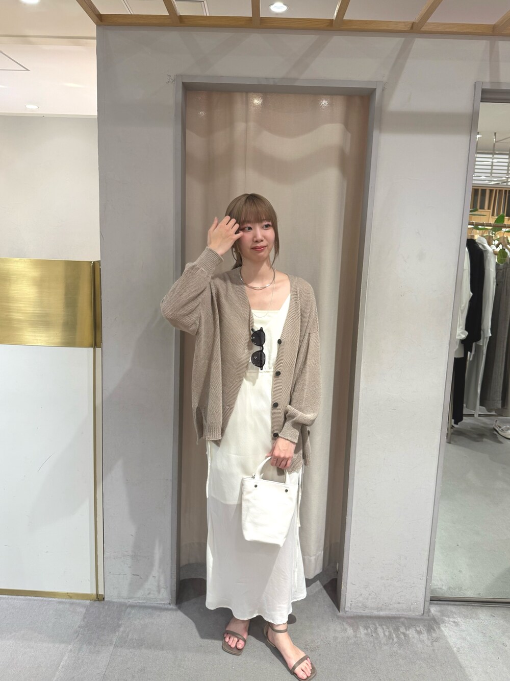 ベージュ系のカーディガン/ボレロ、ホワイト系のワンピース、ホワイト系のトートバッグを着用したレディースの夏コーディネートの2枚目の写真