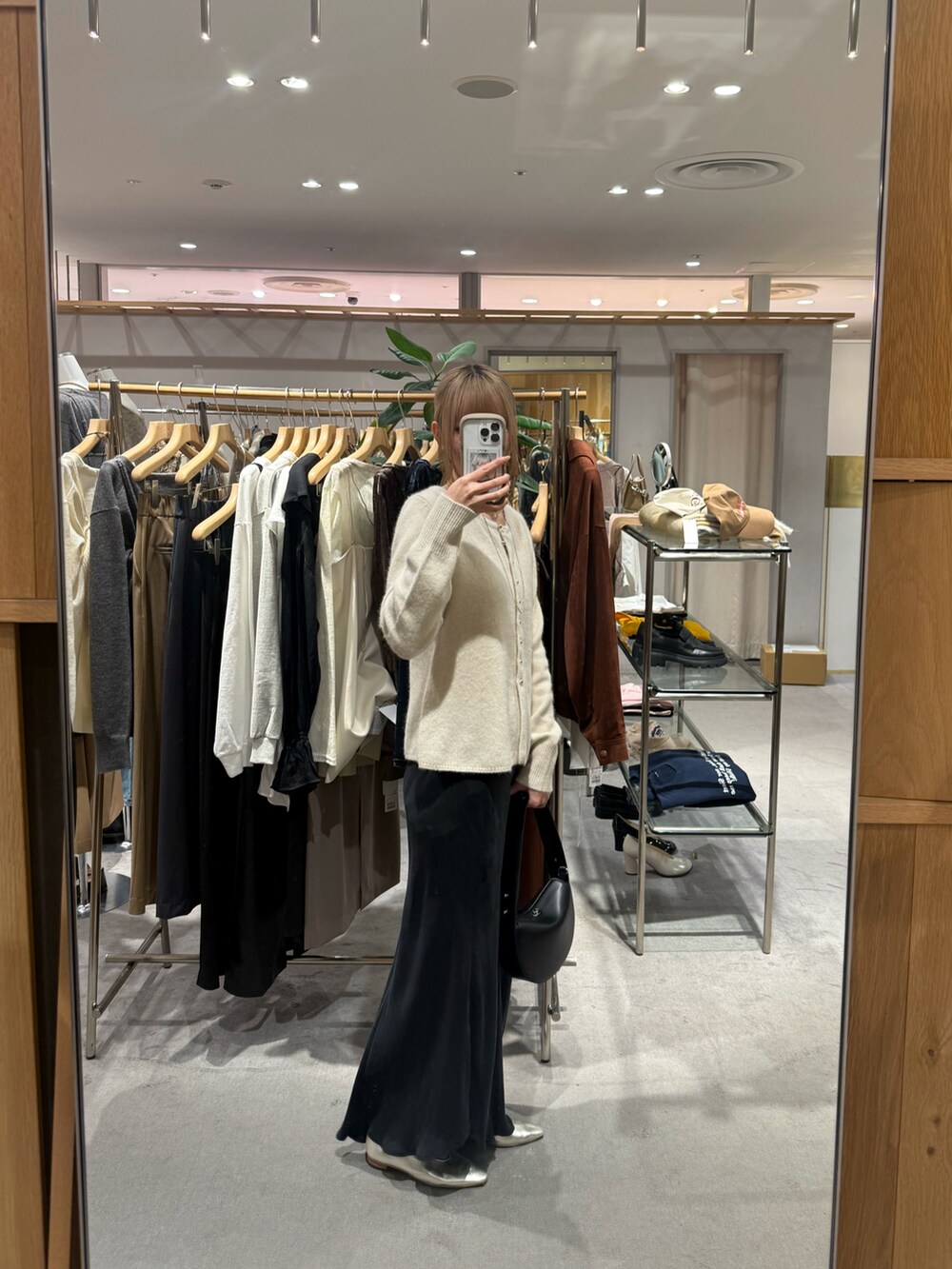 ホワイト系のカーディガン/ボレロ、ブラック系のトートバッグ、ブラック系のスカートを着用したレディースの秋コーディネートの2枚目の写真