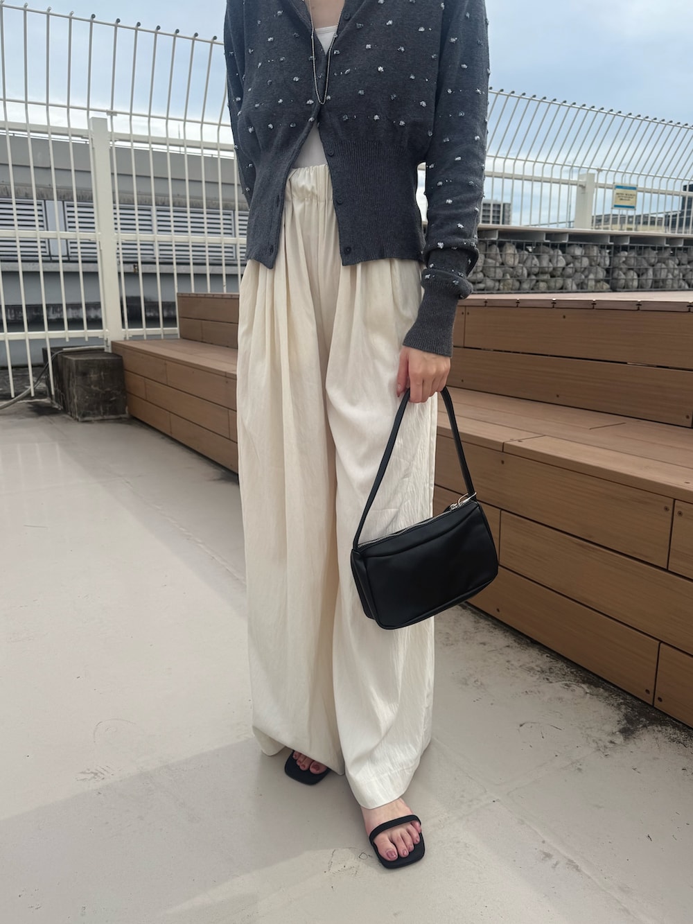 グレー系のカーディガン/ボレロ、ホワイト系のその他パンツ、ブラック系のショルダーバッグを着用したレディースの秋コーディネートの2枚目の写真