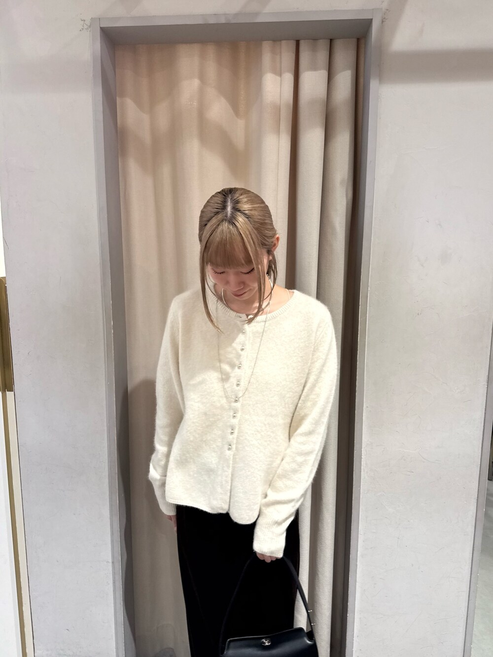 ホワイト系のカーディガン/ボレロ、ブラック系のトートバッグ、ブラウン系のスカートを着用したレディースの秋コーディネートの2枚目の写真