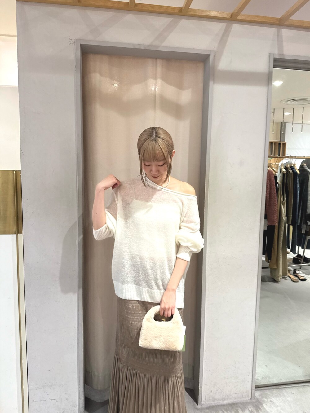ホワイト系のニット/セーター、シルバー系のトートバッグ、ベージュ系のスカートを着用したレディースの秋コーディネートの2枚目の写真