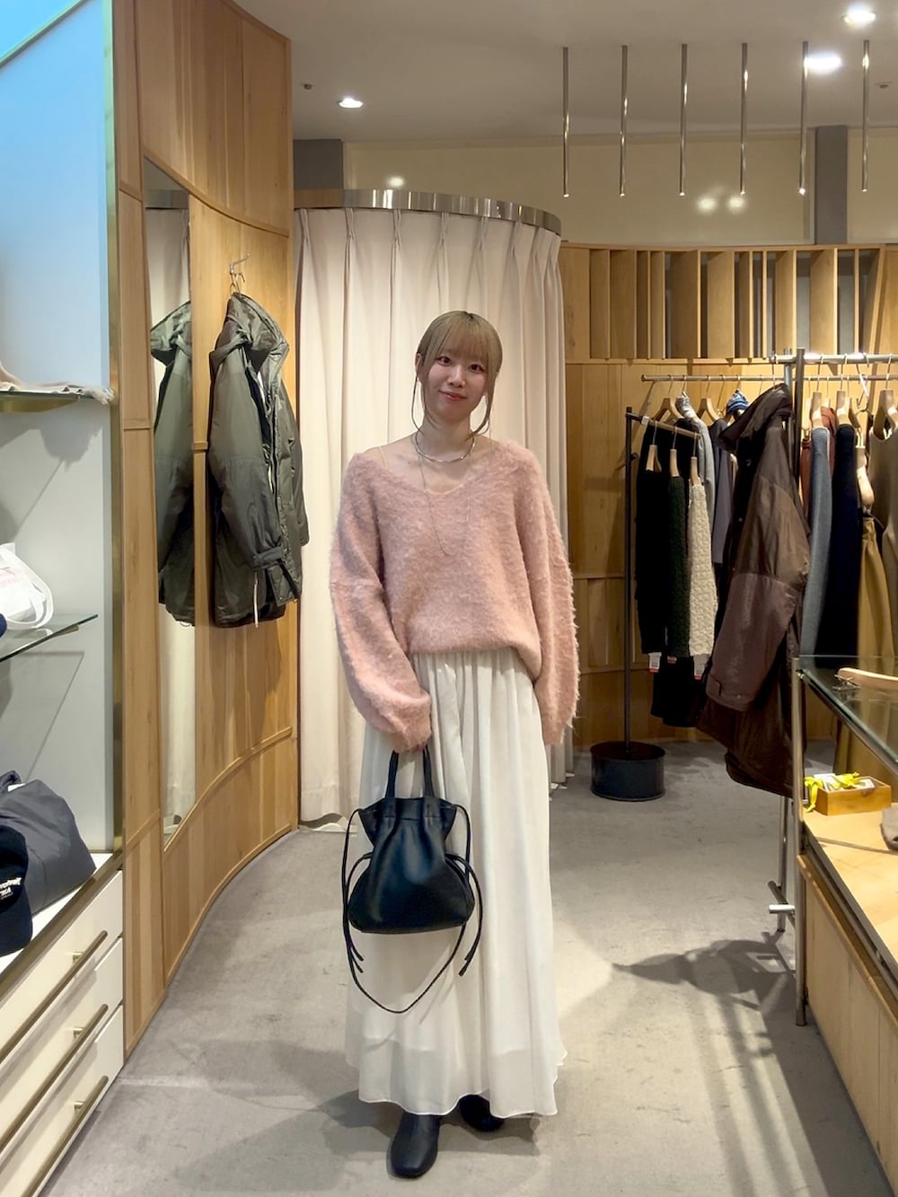 ピンク系のニット/セーター、ブラック系のトートバッグ、ホワイト系のスカートを着用したレディースの冬コーディネートの3枚目の写真