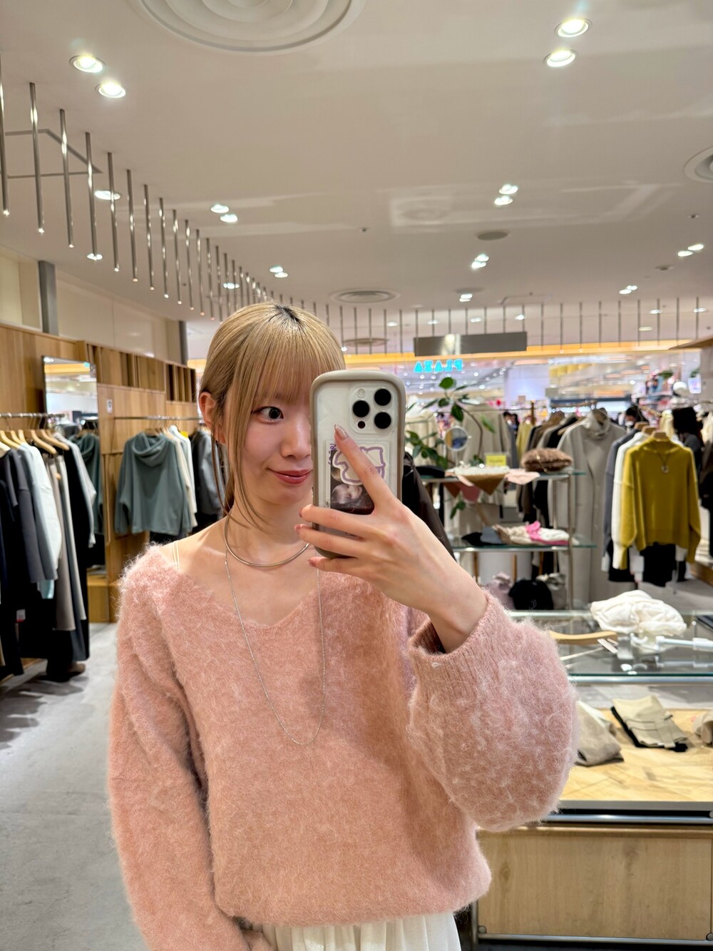 ピンク系のニット/セーター、ブラック系のトートバッグ、ホワイト系のスカートを着用したレディースの冬コーディネートの2枚目の写真