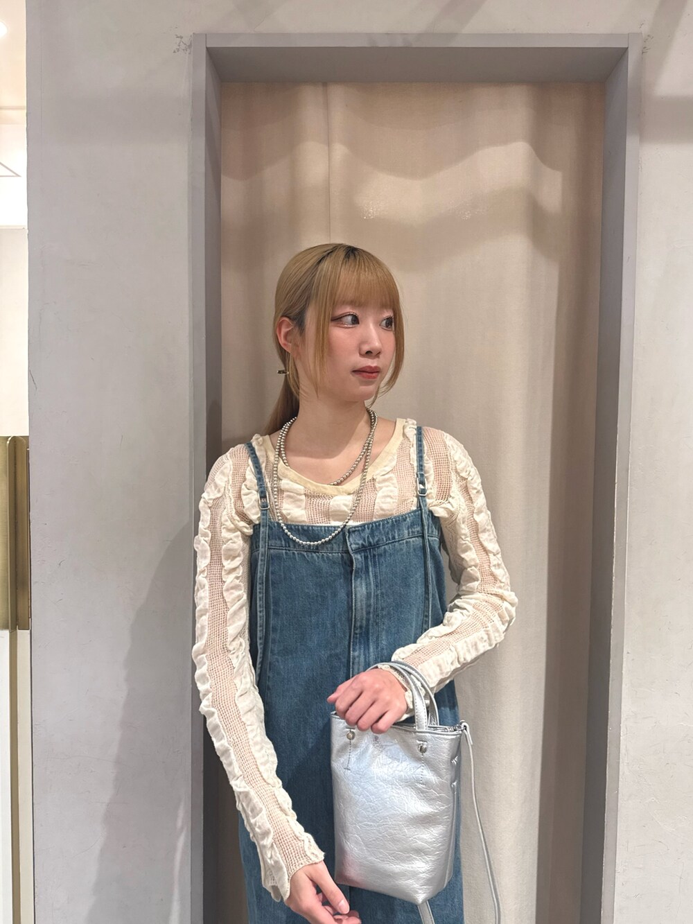 ブルー系のサロペット/オーバーオール、ベージュ系のカーディガン/ボレロ、シルバー系のトートバッグを着用したレディースの春コーディネートの3枚目の写真