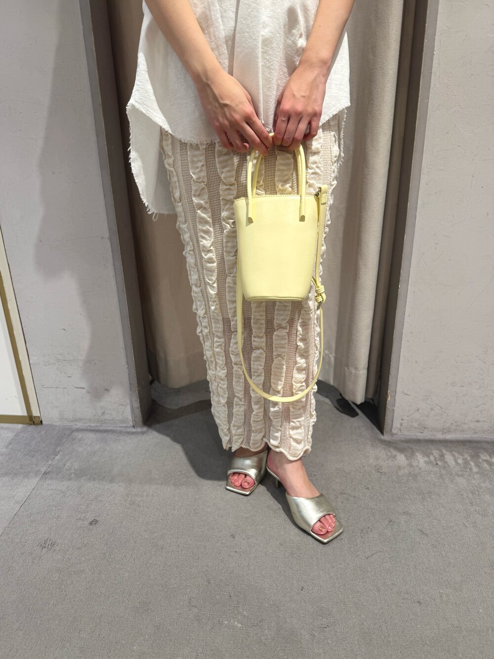 ホワイト系のシャツ/ブラウス、イエロー系のトートバッグ、ベージュ系のスカートを着用したレディースの夏コーディネートの4枚目の写真