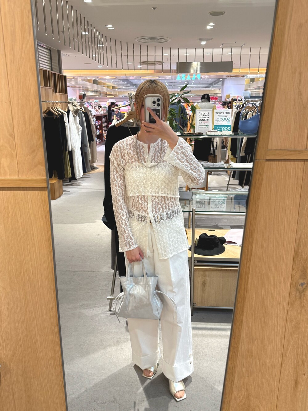 シルバー系のトートバッグ、ホワイト系のデニムパンツ、グレー系のサンダルを着用したレディースの春コーディネートの4枚目の写真