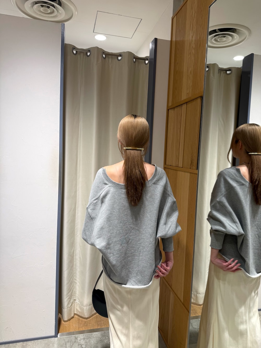 グレー系のスウェット、ブラック系のトートバッグ、ホワイト系のスカートを着用したレディースの春コーディネートの3枚目の写真