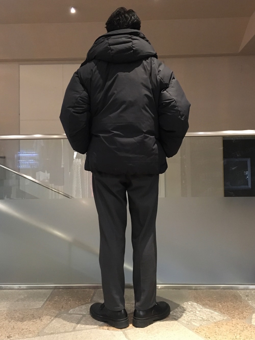 ブラック系のスウェット、ブラック系のダウンジャケット/コート、グレー系のスラックスを着用したメンズの冬コーディネートの3枚目の写真