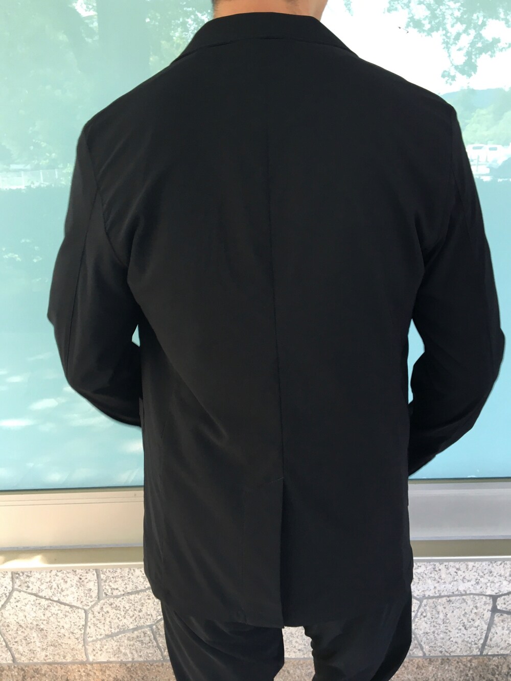 ブラック系のテーラードジャケット、ブラック系のスラックス、ホワイト系のTシャツ/カットソーを着用したメンズの夏コーディネートの5枚目の写真