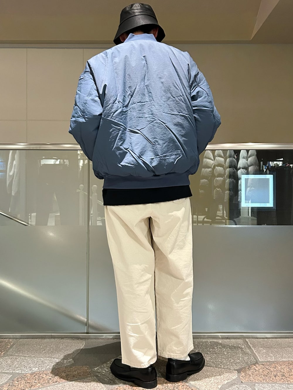 ブルー系のMA-1、ブラック系のカーディガン/ボレロ、ホワイト系のデニムパンツを着用したメンズの冬コーディネートの3枚目の写真