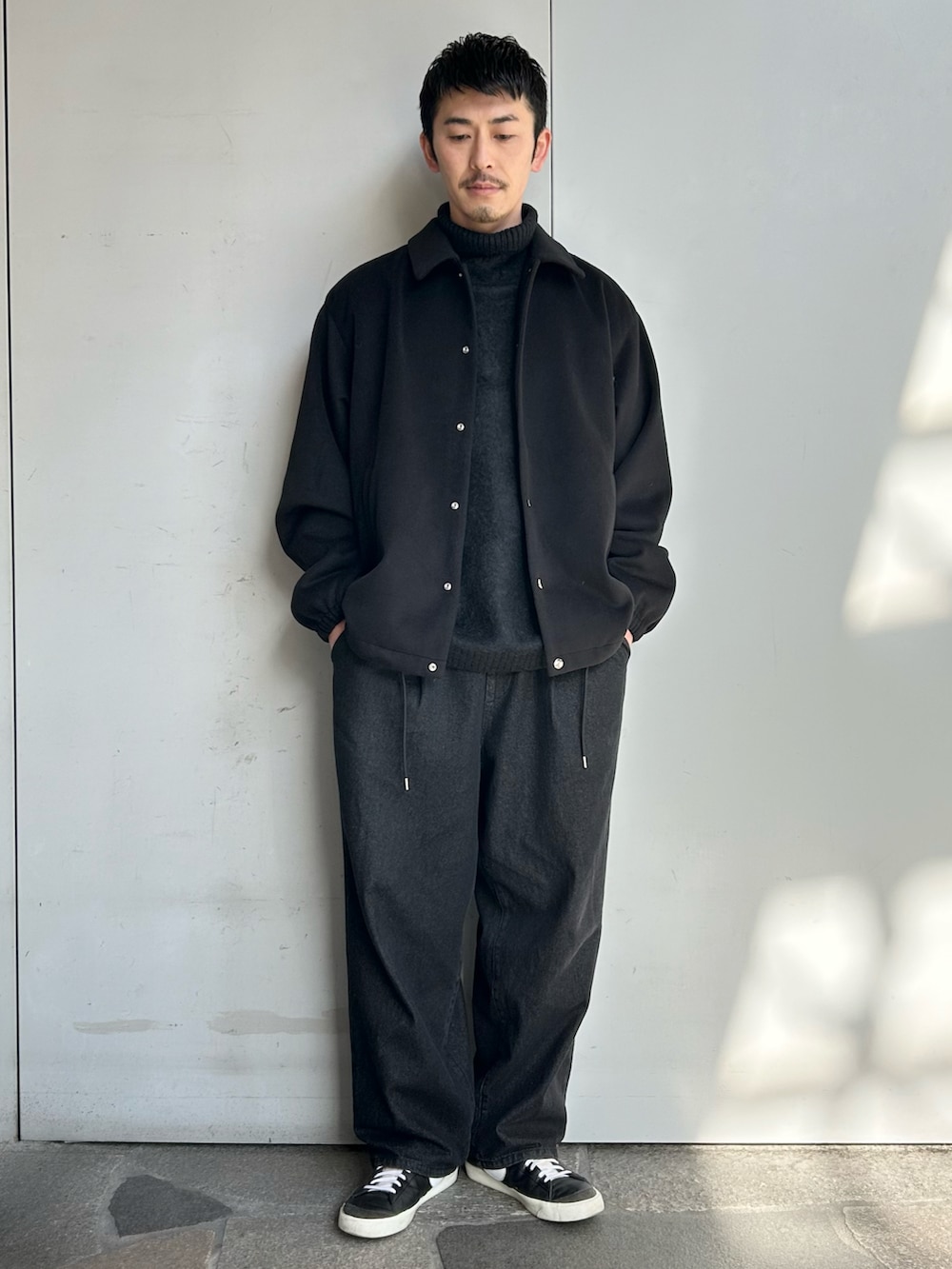 ホワイト系のブルゾン、ブラック系のニット/セーター、ブラック系のデニムパンツを着用したメンズの冬コーディネートの2枚目の写真