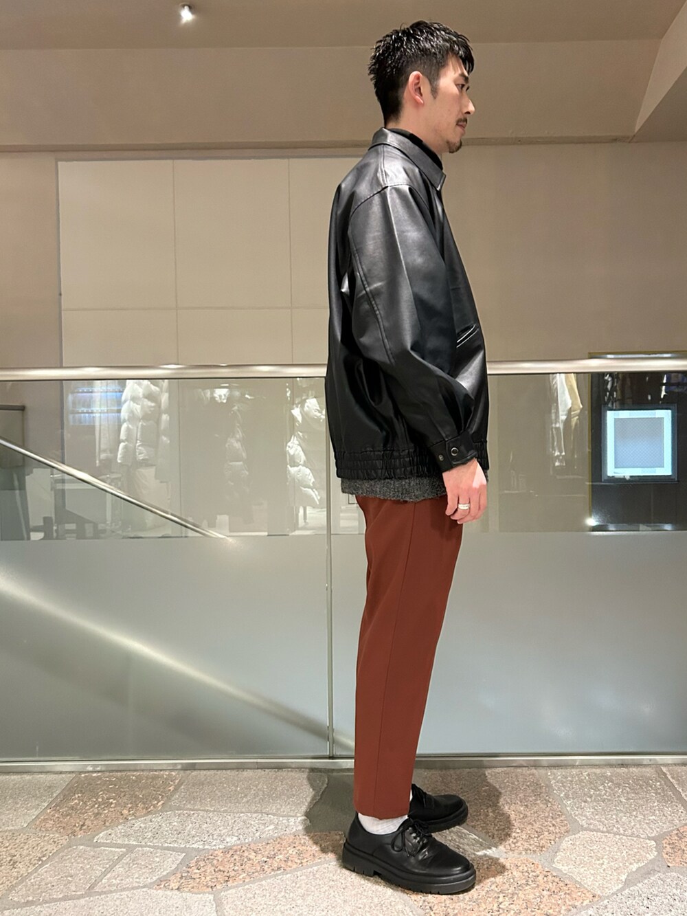 ブラック系のブルゾン、グレー系のニット/セーター、イエロー系のスラックスを着用したメンズの冬コーディネートの2枚目の写真