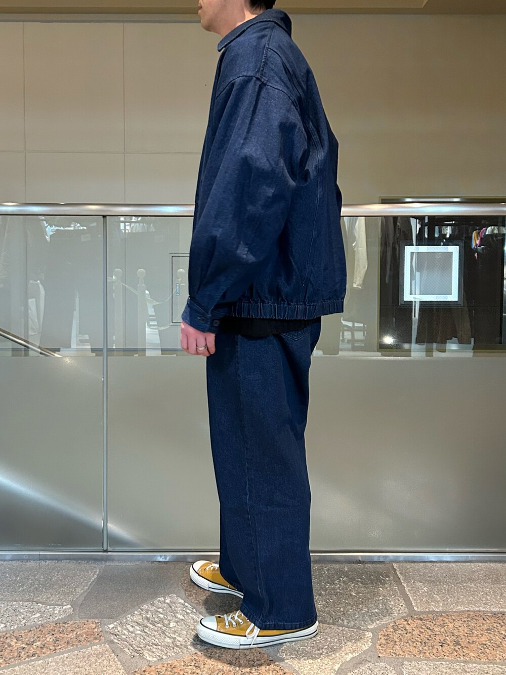 ブルー系のデニムジャケット、ブラック系のニット/セーター、ブルー系のデニムパンツを着用したメンズの春コーディネートの2枚目の写真