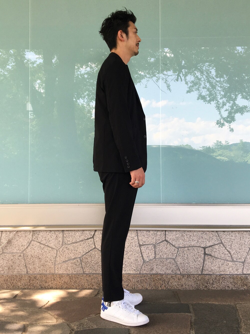 ブラック系のテーラードジャケット、ブラック系のスラックス、ホワイト系のTシャツ/カットソーを着用したメンズの夏コーディネートの3枚目の写真