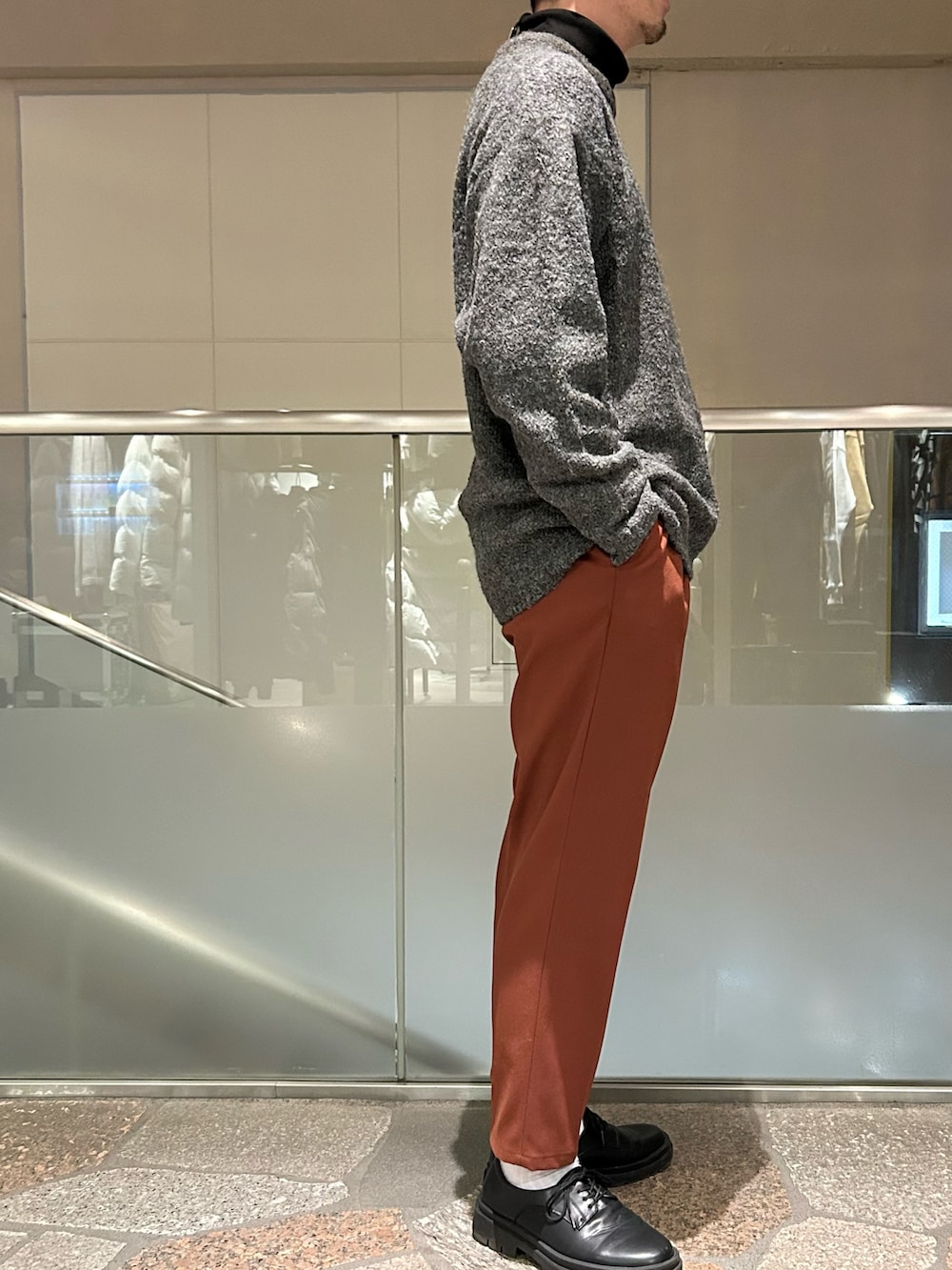 ブラック系のブルゾン、グレー系のニット/セーター、イエロー系のスラックスを着用したメンズの冬コーディネートの3枚目の写真