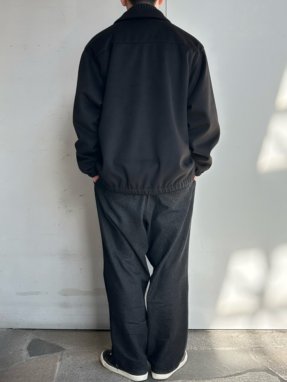 ホワイト系のブルゾン、ブラック系のニット/セーター、ブラック系のデニムパンツを着用したメンズの冬コーディネートの3枚目の写真