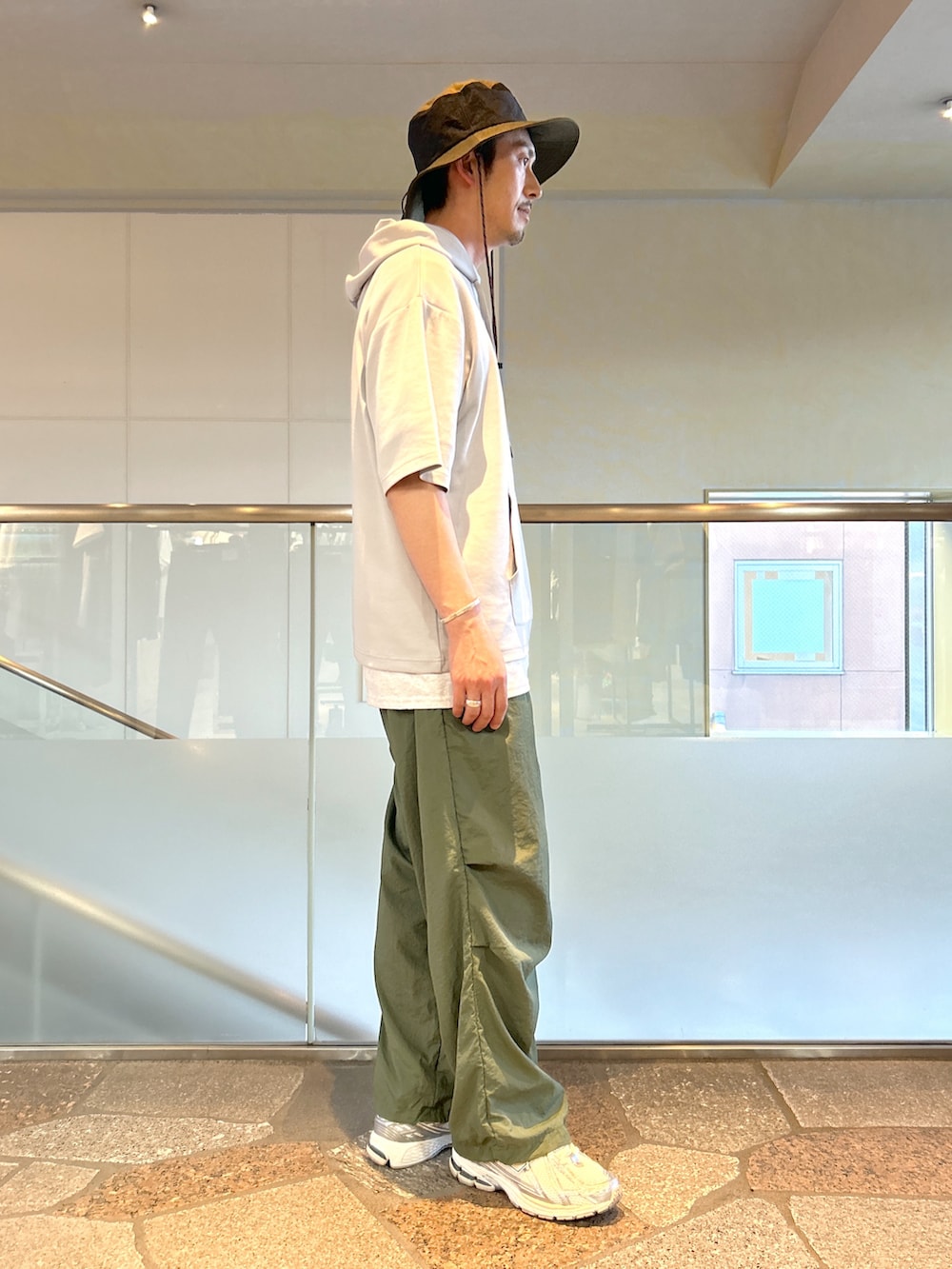 グレー系のTシャツ/カットソー、グリーン系のカーゴパンツを着用したメンズの夏コーディネートの2枚目の写真