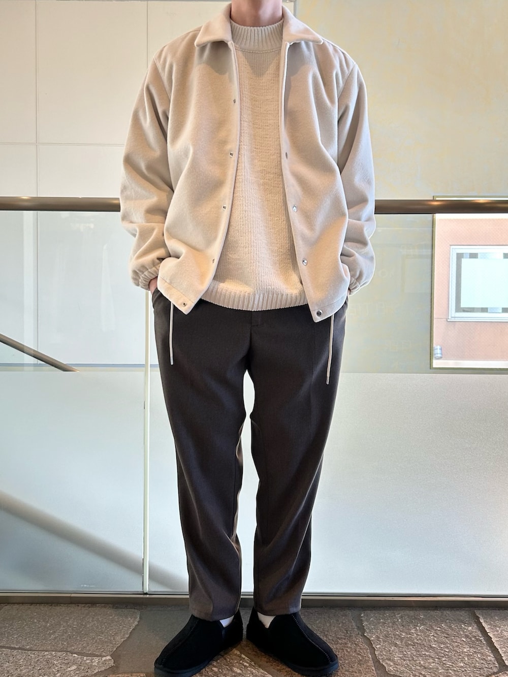 ホワイト系のブルゾン、ホワイト系のニット/セーター、イエロー系のスラックスを着用したメンズの冬コーディネートの2枚目の写真