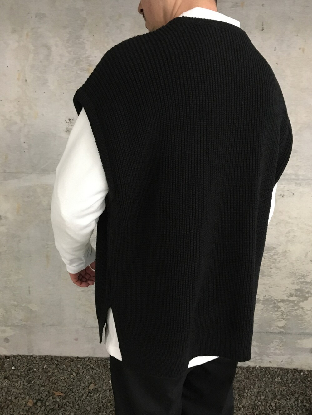ブラック系のベスト、ホワイト系のTシャツ/カットソー、ブラック系のスラックスを着用したメンズの冬コーディネートの4枚目の写真