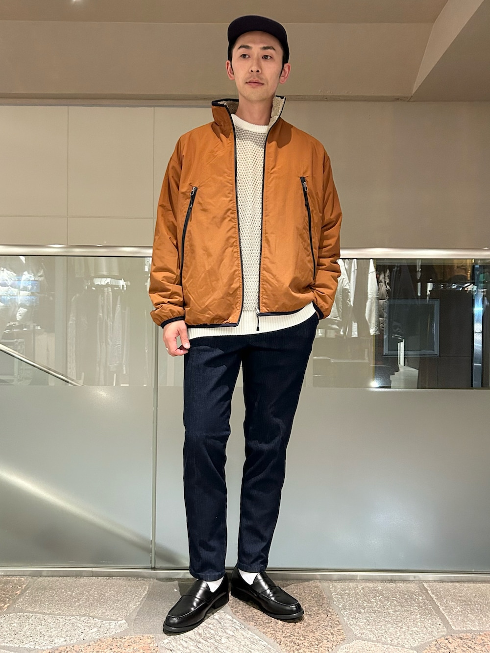 ベージュ系のブルゾン、ホワイト系のニット/セーター、ブルー系のデニムパンツを着用したメンズの秋コーディネートの2枚目の写真