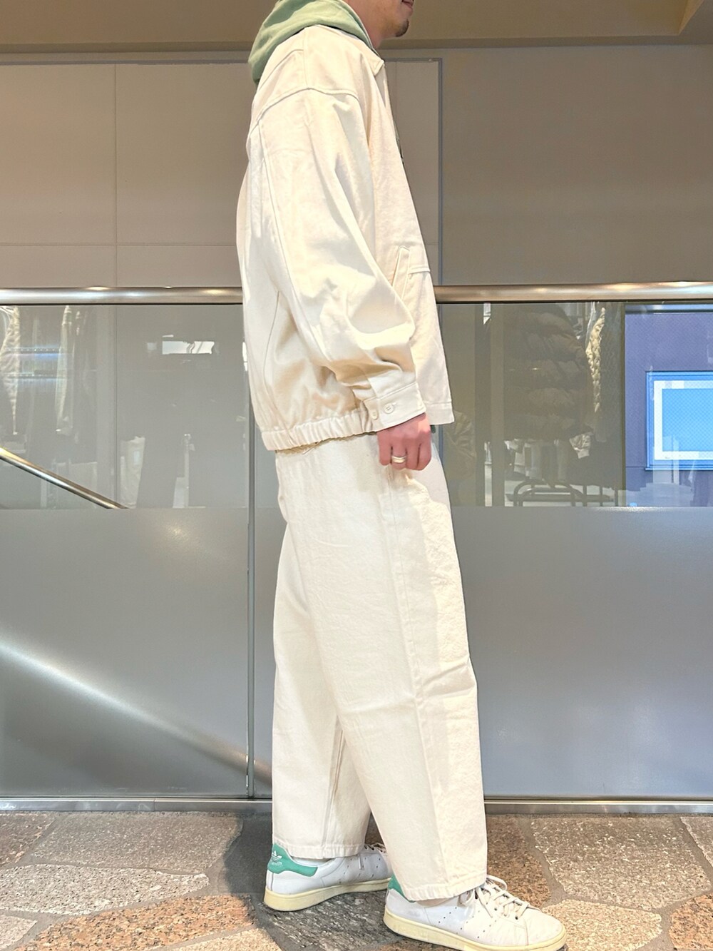 ホワイト系のデニムジャケット、グリーン系のパーカー、ホワイト系のデニムパンツを着用したメンズの春コーディネートの2枚目の写真