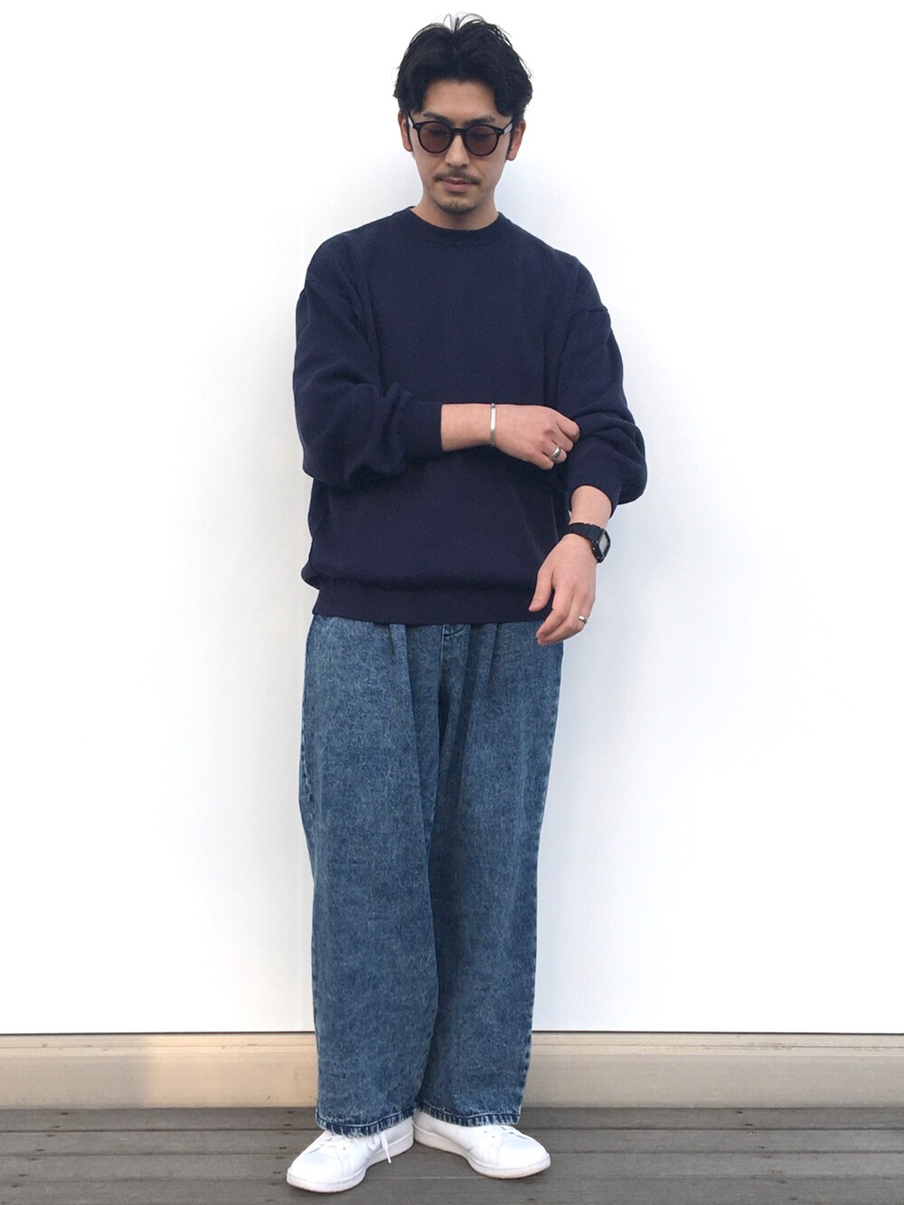 ブルー系のニット/セーター、ブルー系のデニムパンツ、ホワイト系のスニーカーを着用したメンズの春コーディネートの2枚目の写真